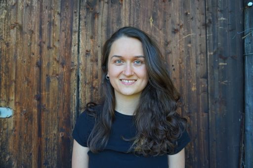 Junge Frau vor brauner Holzwand.