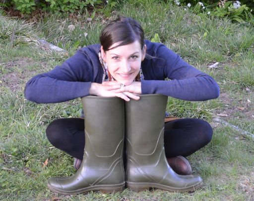 Junge Frau sitzt hinter ihren grossen Gummitstiefeln
