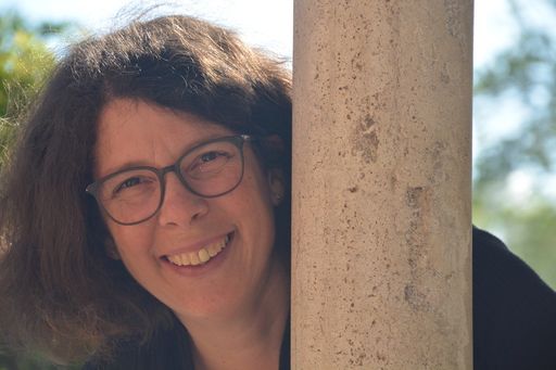 Lachende Frau mit braunen Haaren und Brille.