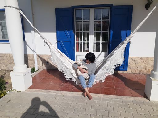 Frau sitzt mit Hund in Hängematte